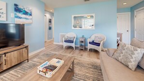 A living room with a TV, two white chairs, a sofa, and a coffee table. - 1st Floor, Near Ferry ,Shared Pool, Golf Cart Access (Port Aransas)