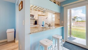 A modern kitchen with white cabinets, a granite countertop, and a view of the backyard through a glass door. - 1st Floor, Near Ferry ,Shared Pool, Golf Cart Access (Port Aransas)