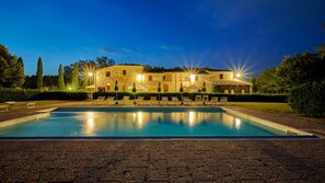 Relax by the pool surrounded by lush greenery and comfortable lounge chairs.