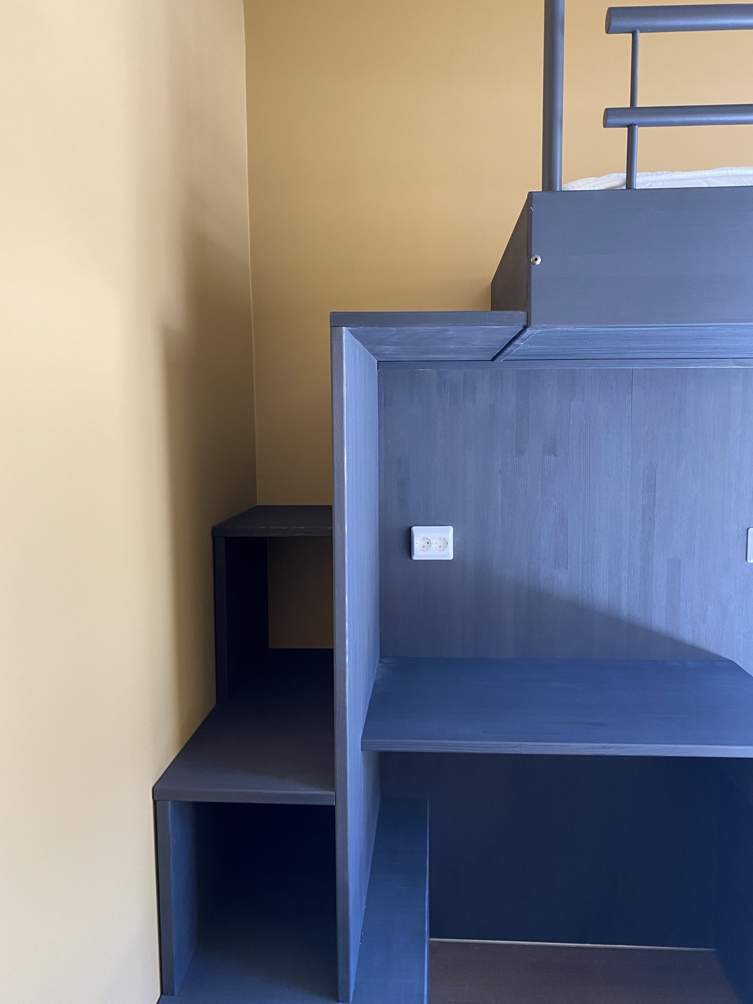 Ein Teil des Raumes mit blauer Wand und einer Holztreppe.