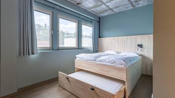 A bedroom with a wooden bed, a window with curtains, and a view of the outside.