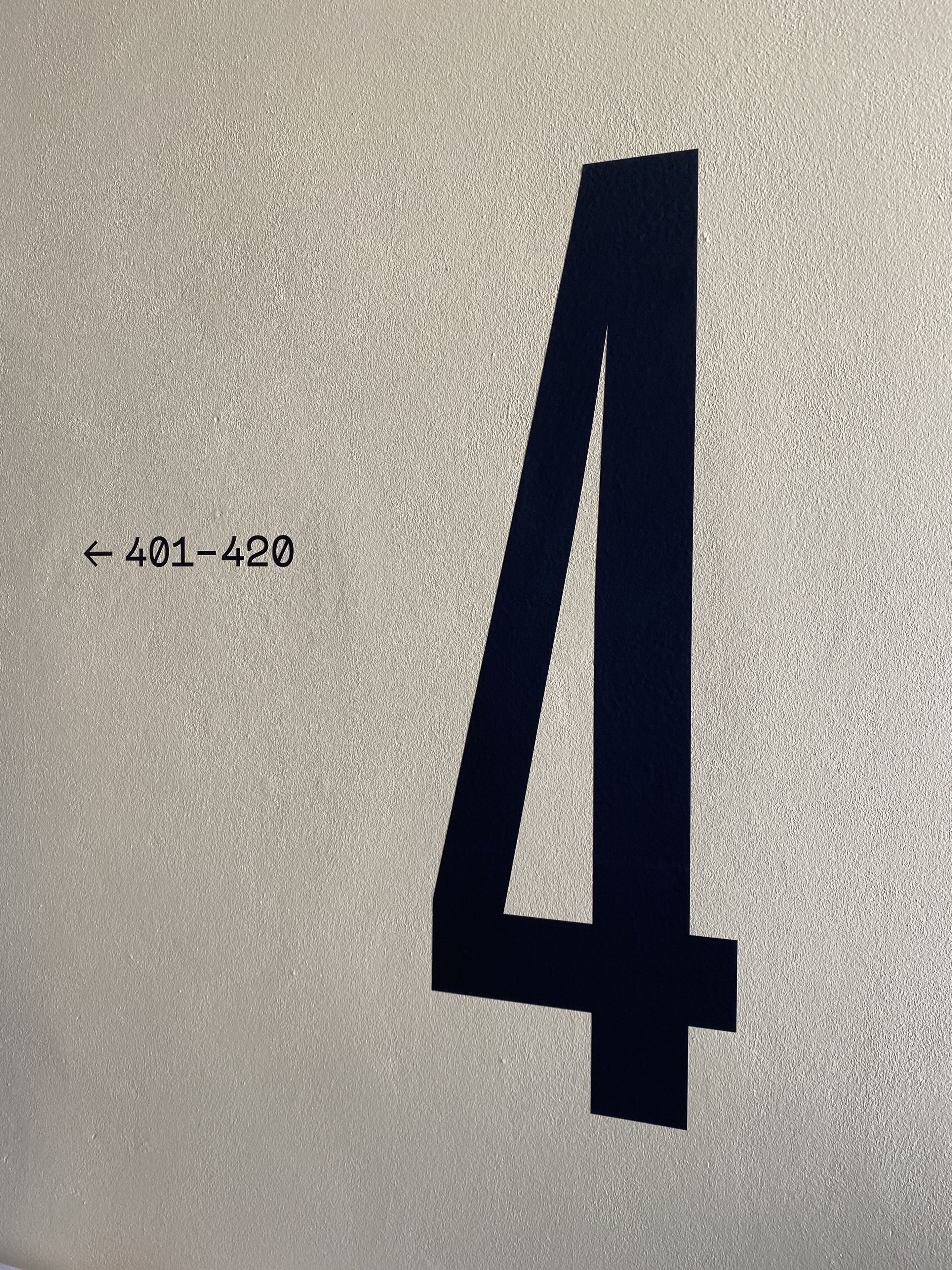 Un número 4 grande y negro sobre una pared beige con textura.