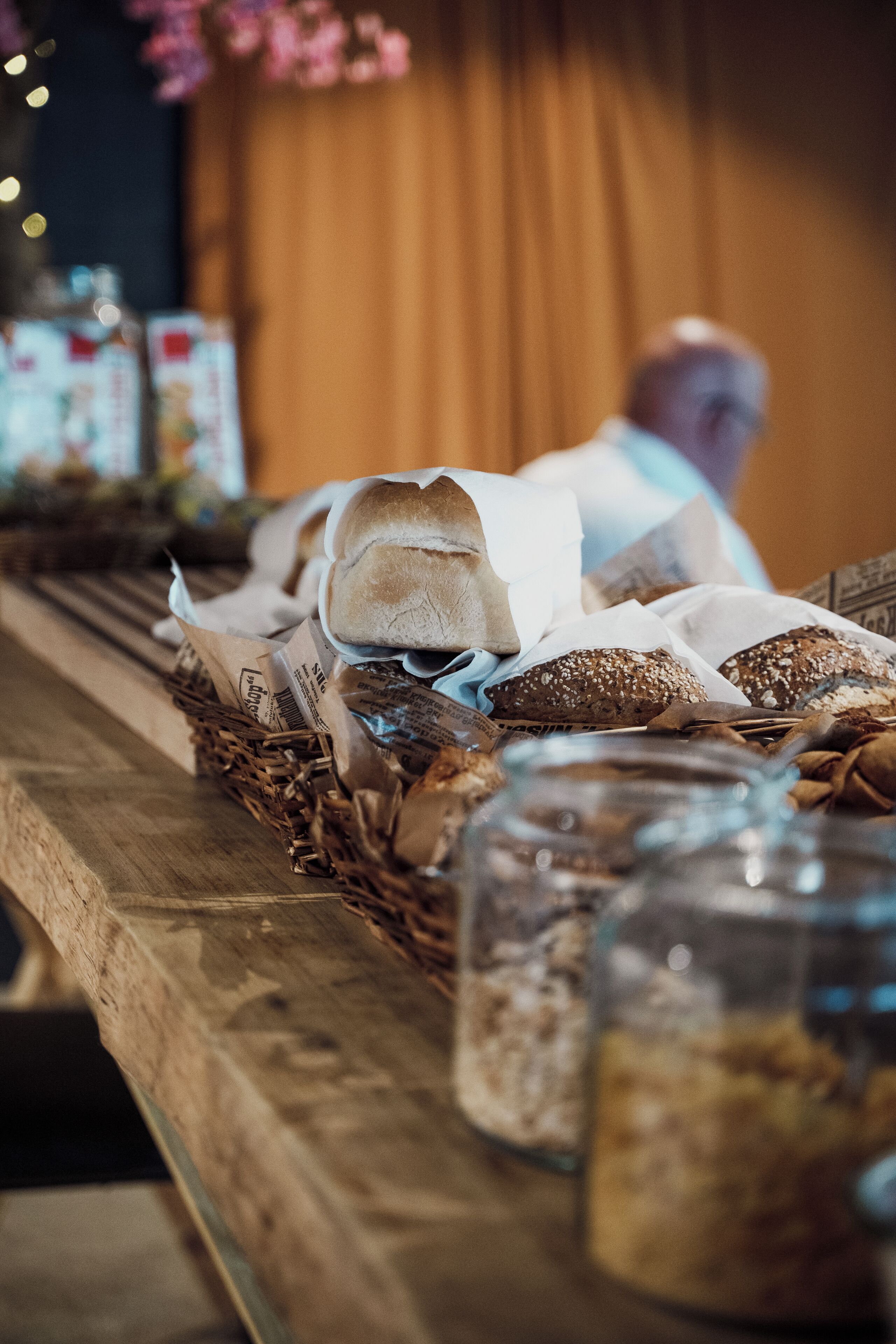 A wooden table with various breads and jars of spreads.