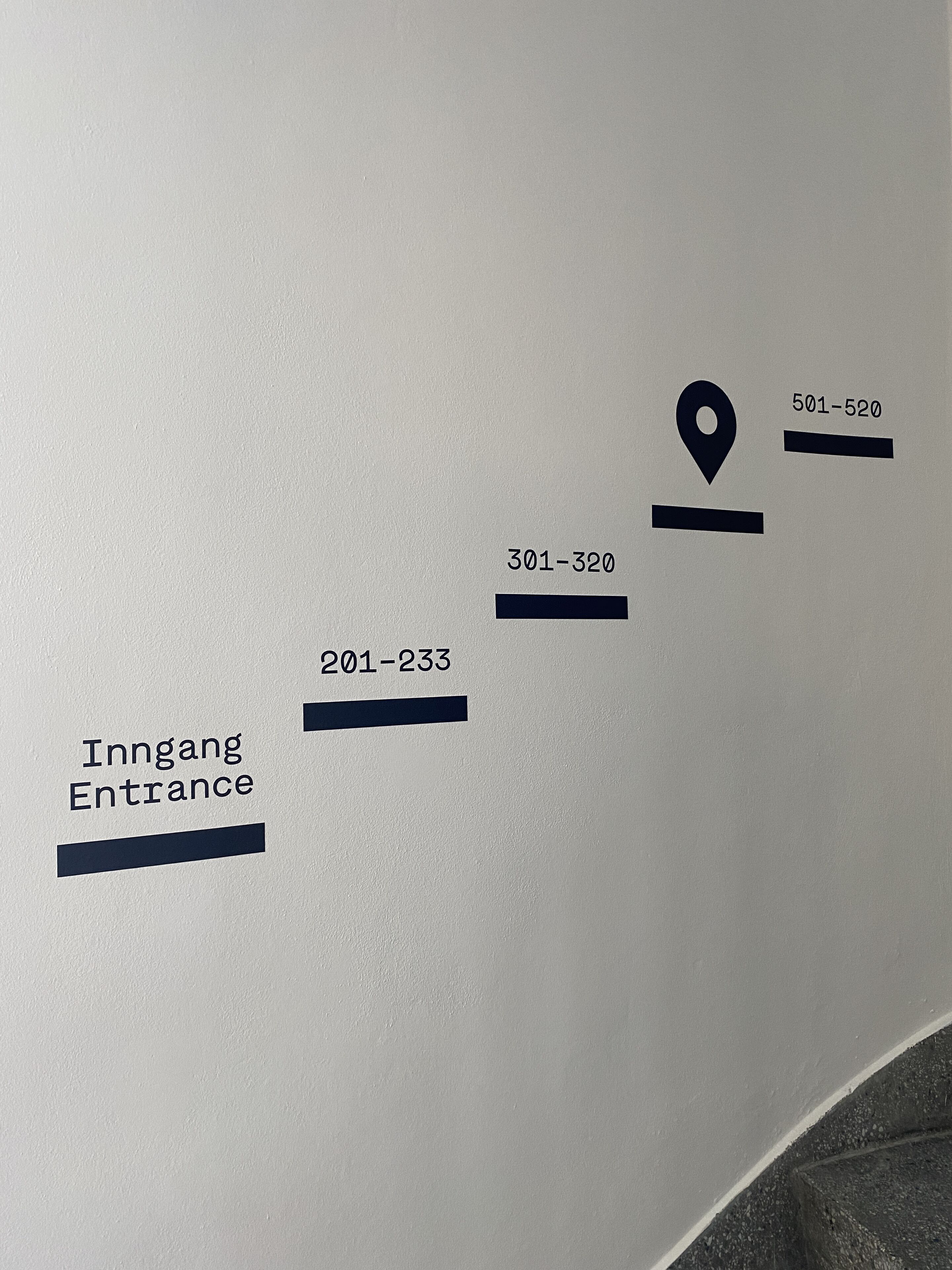 Un mur sur lequel sont affichés des panneaux de signalisation et des numéros indiquant les différentes sections ou pièces.