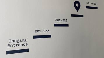 Un mur sur lequel sont affichés des panneaux de signalisation et des numéros indiquant les différentes sections ou pièces.