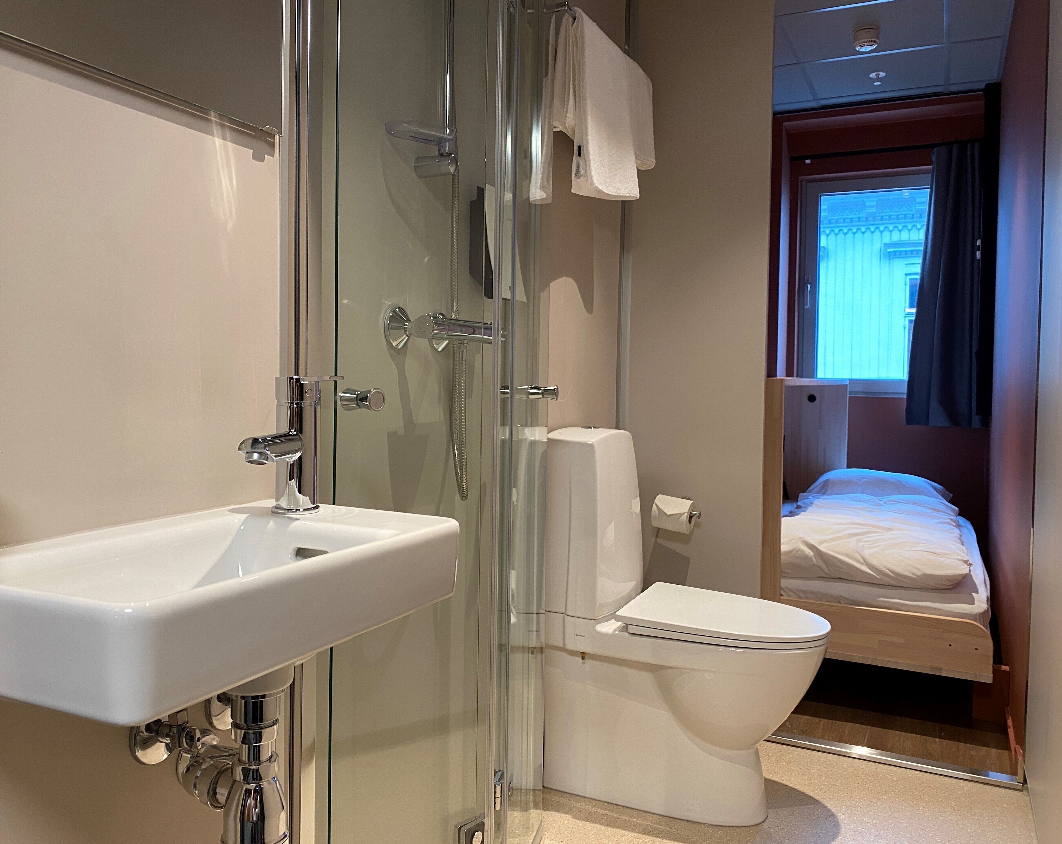 A modern bathroom with a glass shower enclosure, a white sink, and a toilet.