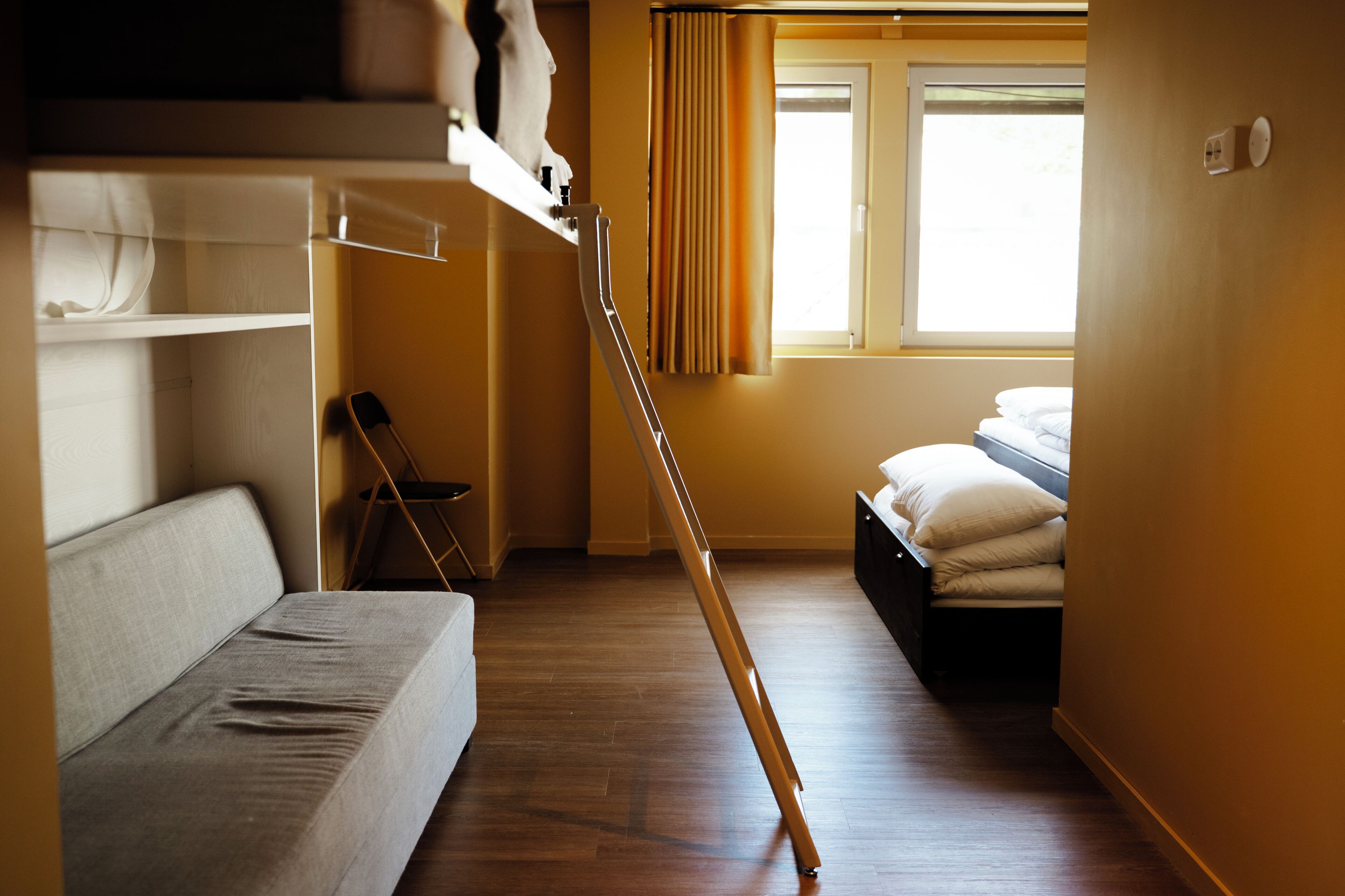 A compact room with bunk beds, a small desk, and a window with curtains.