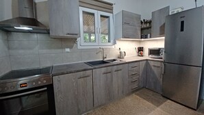 Una cocina moderna con armarios grises, horno de acero inoxidable, microondas integrado y refrigerador.