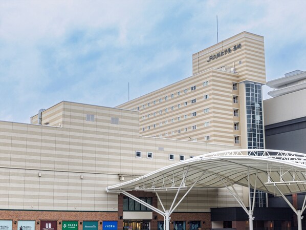 Un hotel con un diseño arquitectónico moderno, que destaca por una fachada rayada y una gran estructura blanca en arco al frente.