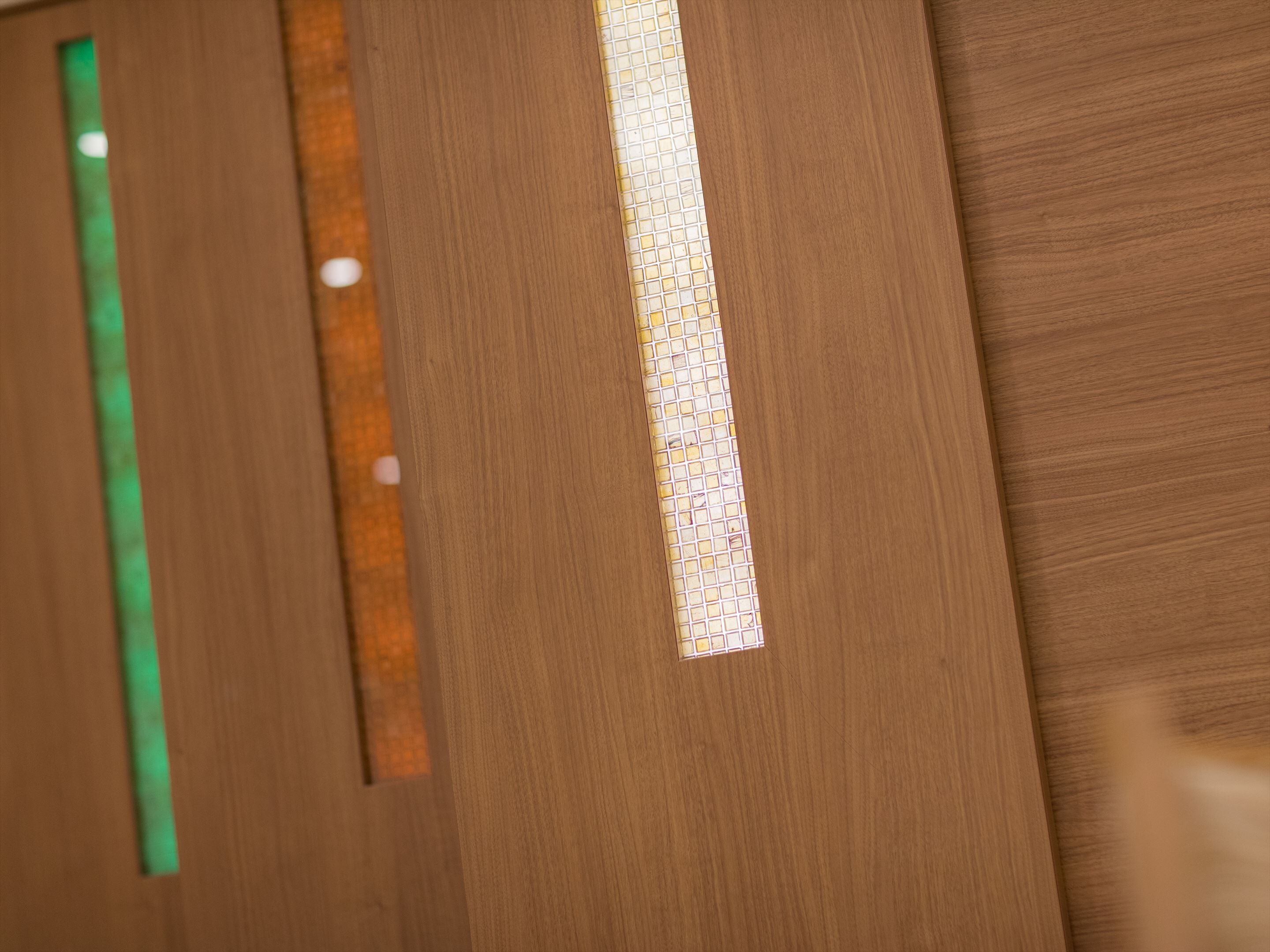 Una puerta de madera con una franja vertical de vidrio con diseño.
