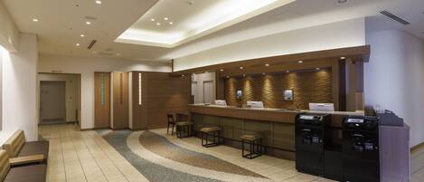 A modern reception area with a counter, seating, and a patterned rug.