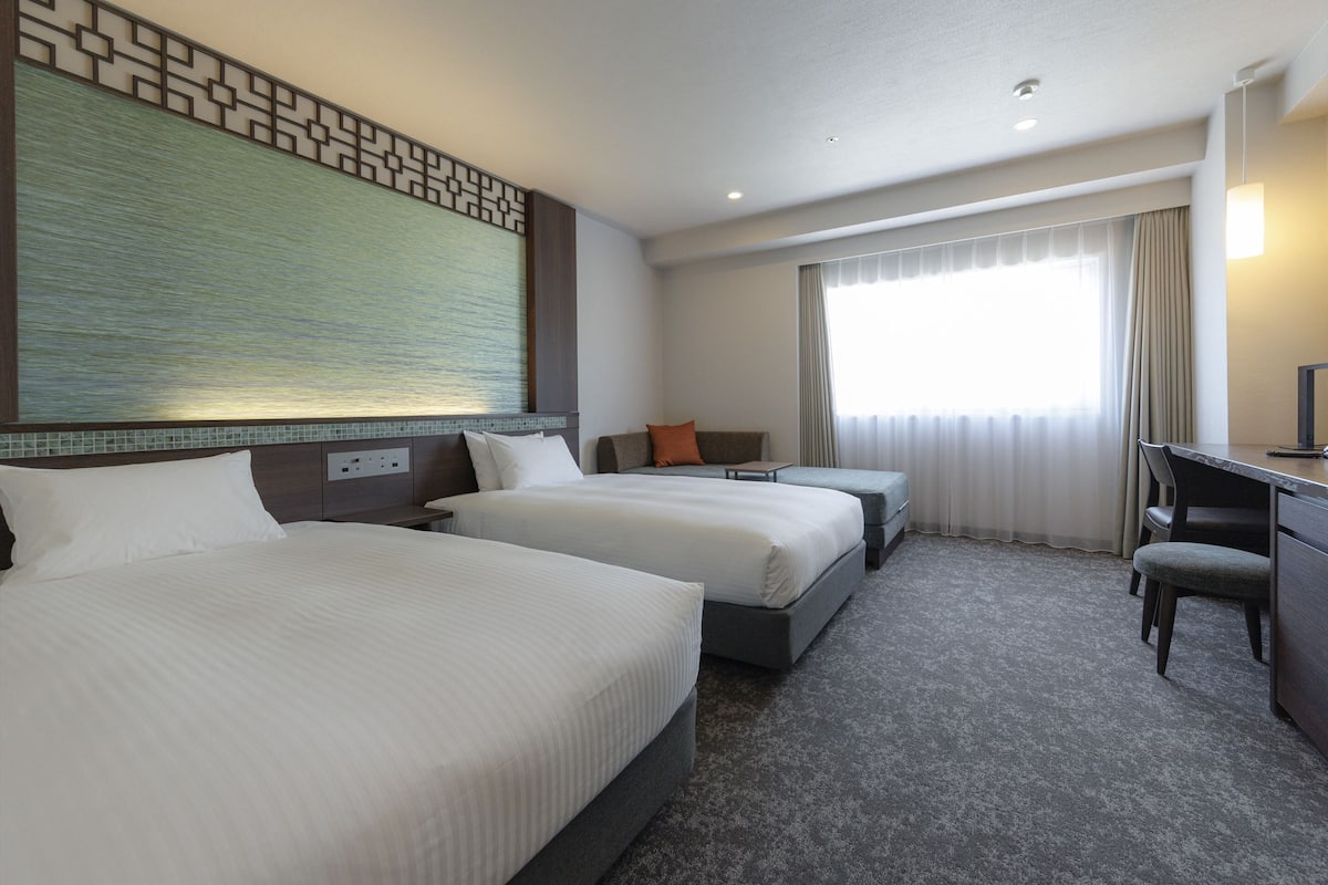 Una habitación de hotel con dos camas, un escritorio y una silla.