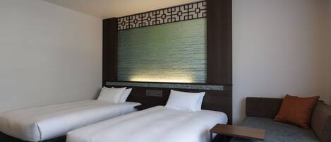 Habitación de hotel con dos camas individuales, un sofá y una mesita.