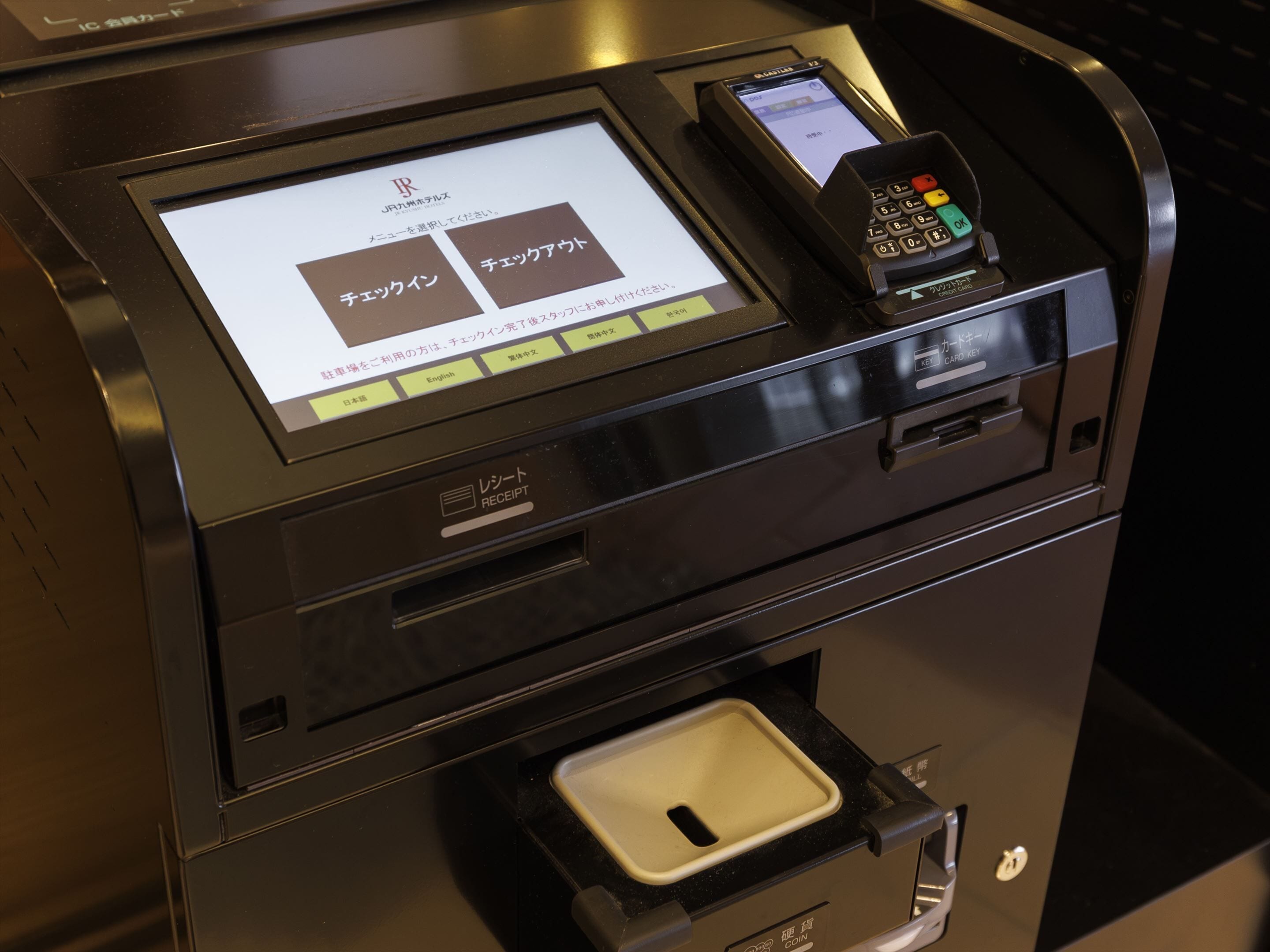 A self-service kiosk with a receipt printer, a card reader, and a coin slot.