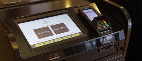 A self-service kiosk with a receipt printer, a card reader, and a coin slot.
