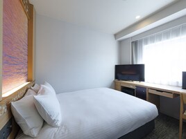 Una habitación de hotel con una cama, televisión y ventana con cortinas.