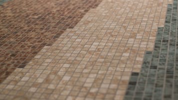 Un primo piano di un pavimento piastrellato con un motivo di piccole tessere quadrate in diverse tonalità di marrone e beige.