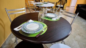 A dining area with a round table set for two, featuring green placemats and white plates with blue patterns. - LA DIMORA DEL PRINCIPE (Trapani)