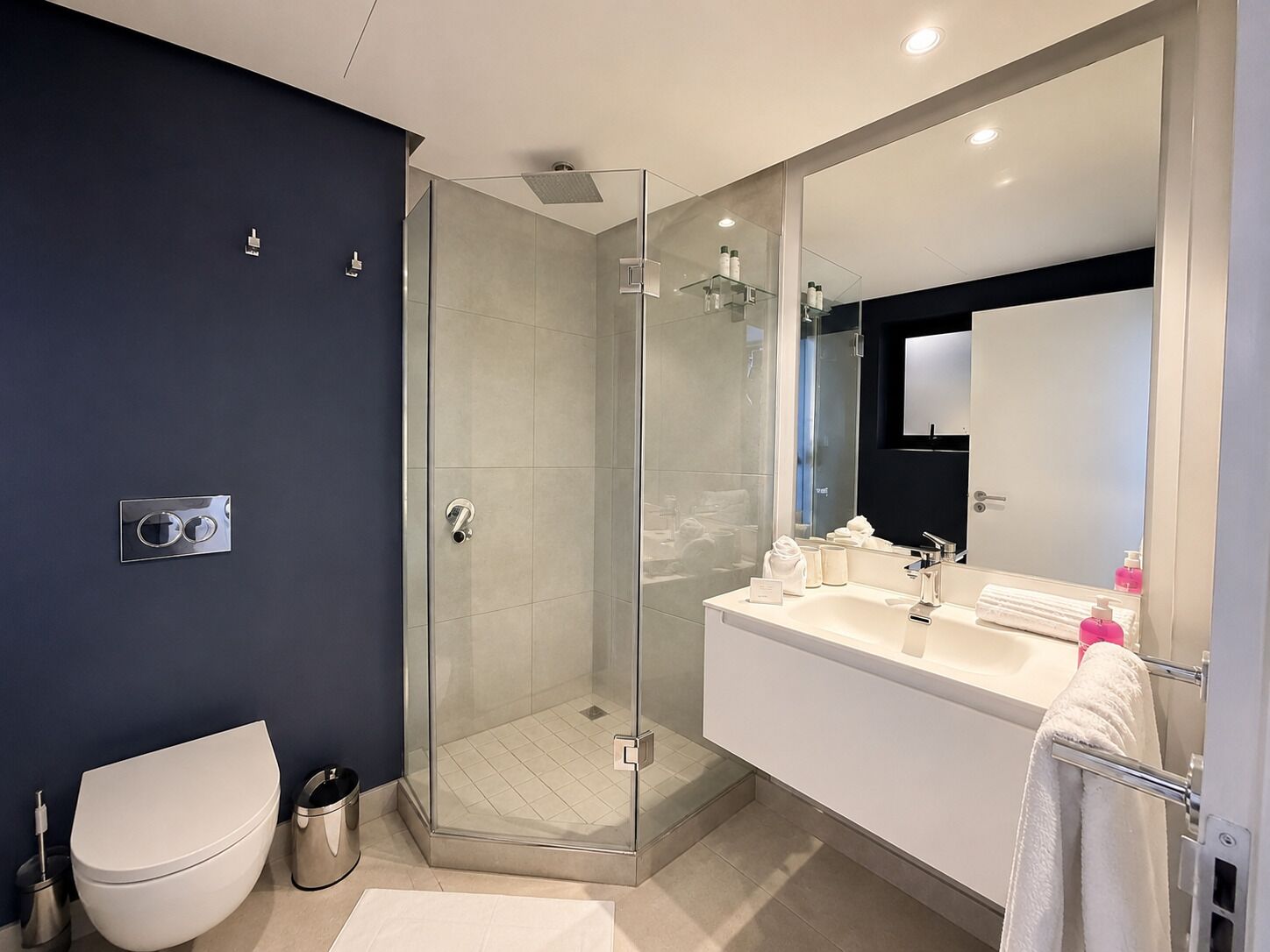 A modern bathroom with a glass-enclosed shower, a white toilet, and a vanity with a mirror.