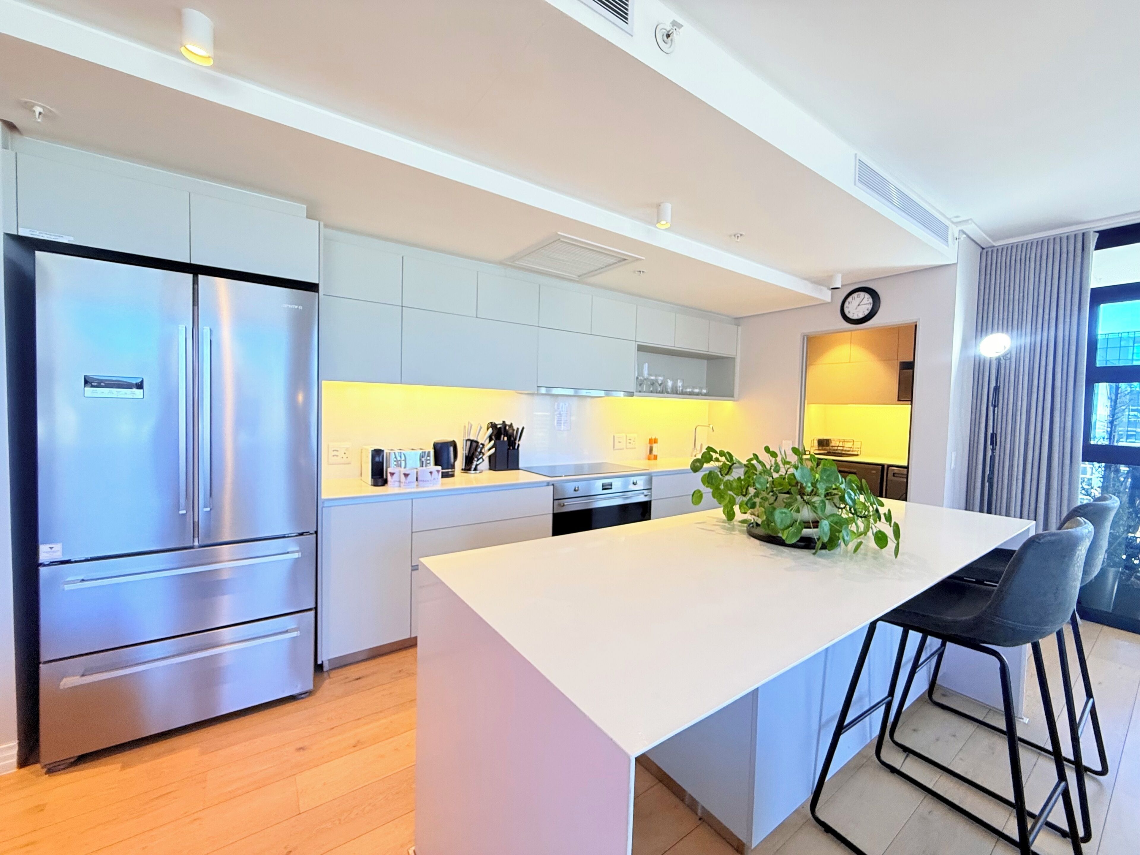 A modern kitchen with a central island, stainless steel appliances, and a view of the outdoors.
