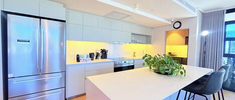 A modern kitchen with a central island, stainless steel appliances, and a view of the outdoors.