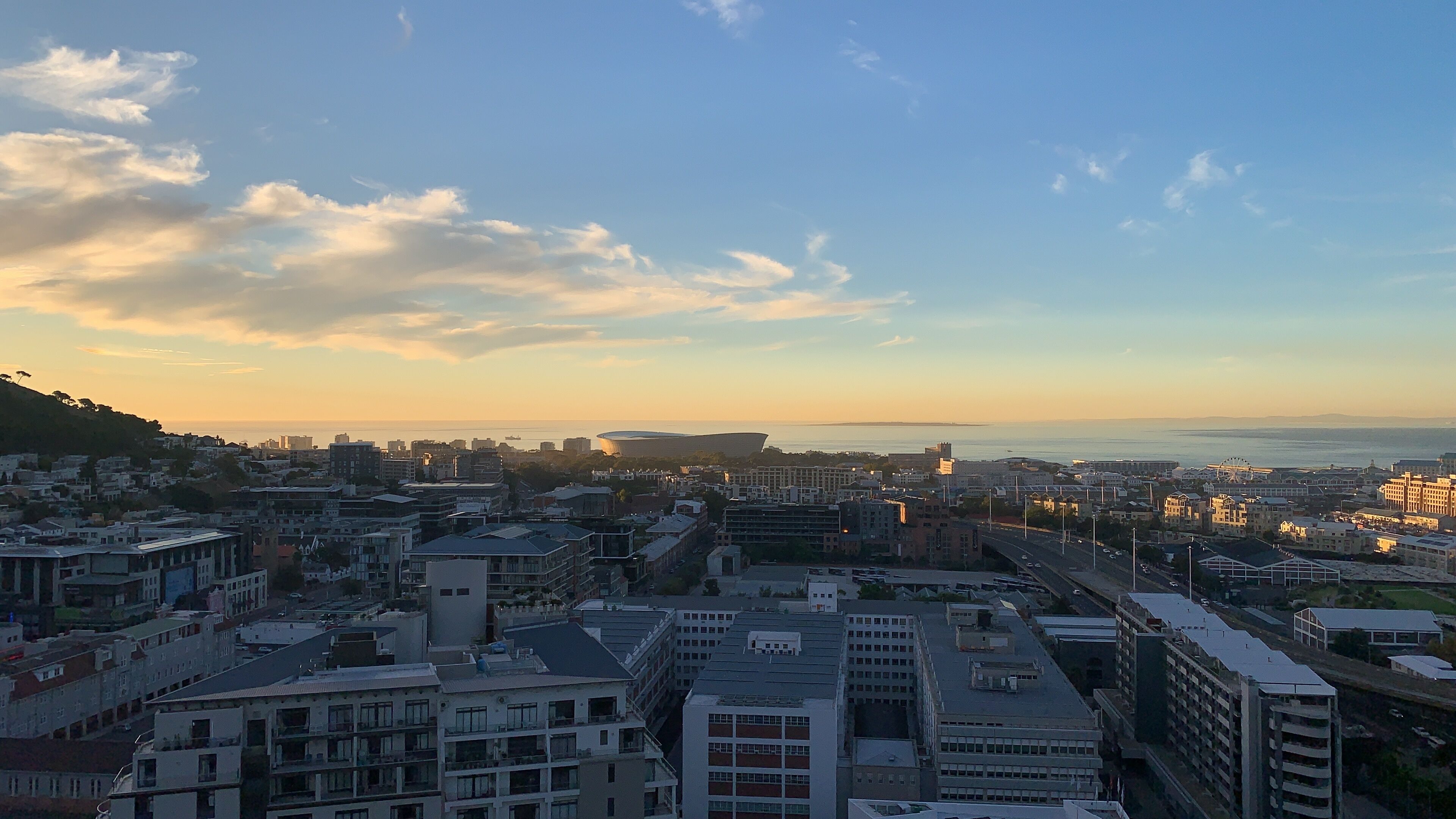 A cityscape with a variety of buildings, including residential and commercial structures, under a clear sky with some clouds.