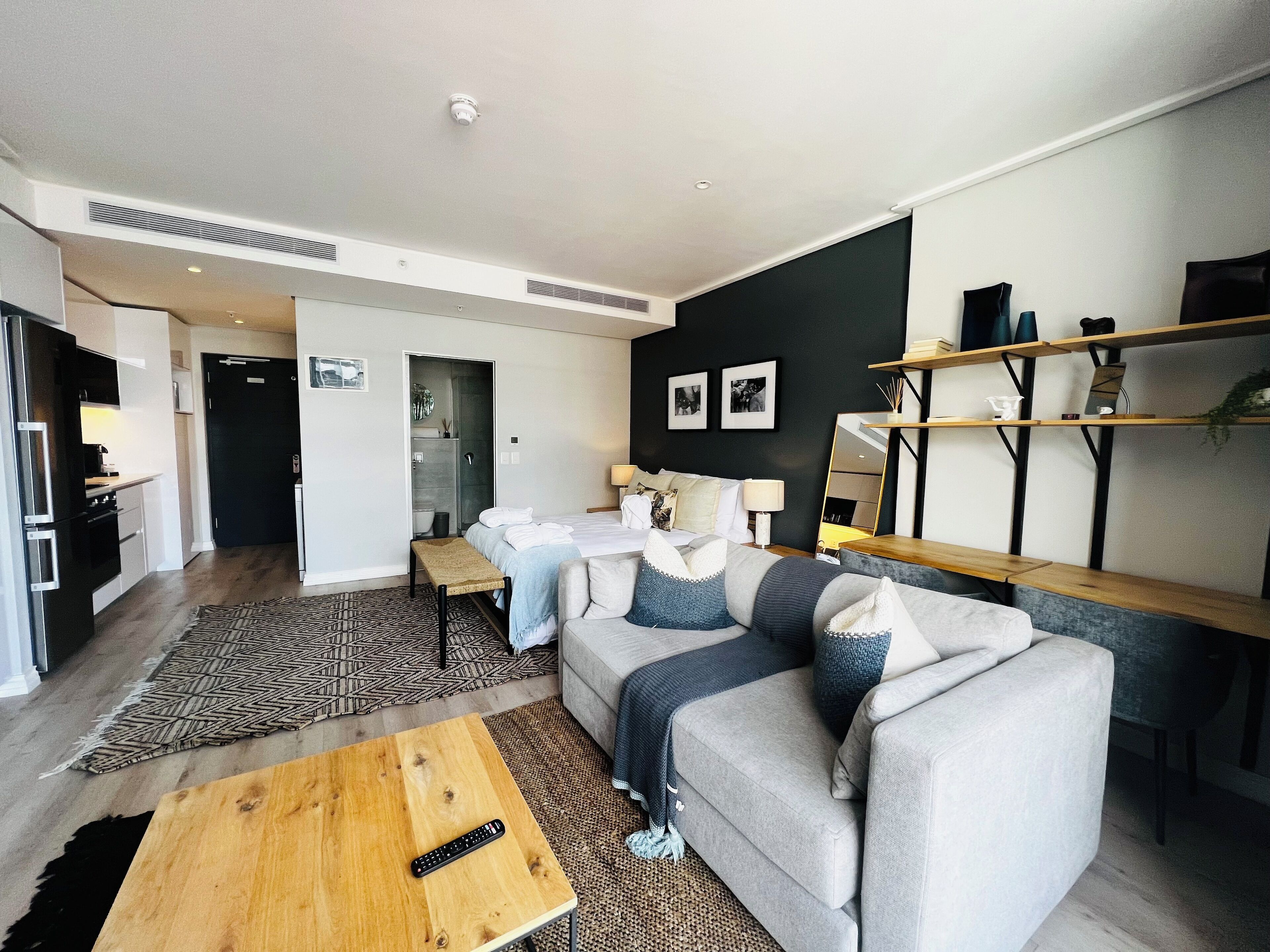 A modern living room with a sofa, coffee table, and a TV remote on the table.
