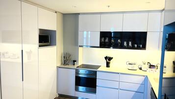 Eine moderne Küche mit weißen Schränken, einem eingebauten Backofen und einer Mikrowelle.
