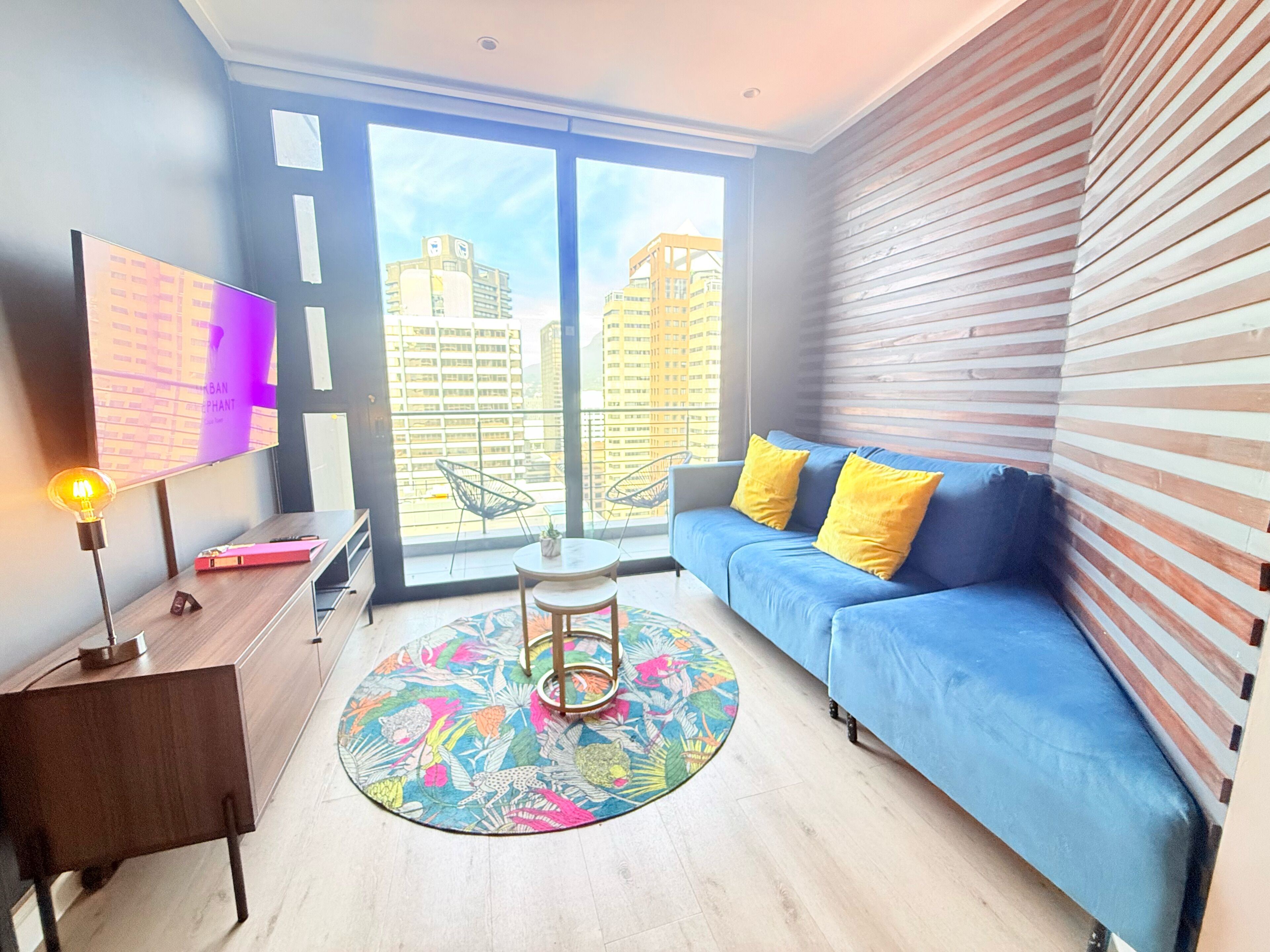 A modern living room with a blue sofa, a round coffee table, and a television on a wooden stand.
