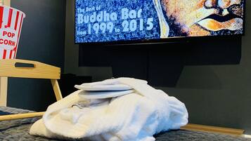 Ein Zimmer mit einem Bett, einem Fernseher, der eine Buddha Bar Veranstaltung zeigt, und einer Popcornschüssel.