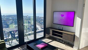 Una sala de estar moderna con un televisor grande, un sofá y una mesa de centro.