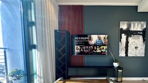 A modern living room with a large TV on a black stand, a wooden coffee table, and a potted plant. - Urban Elephant 16 on Bree (Cape Town)