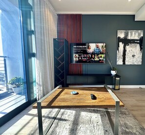 A modern living room with a large TV on a black stand, a wooden coffee table, and a potted plant. - Urban Elephant 16 on Bree (Cape Town)