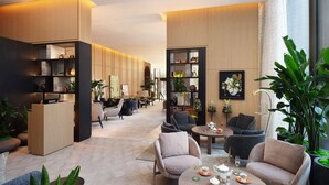 A modern lounge area with seating, a coffee table, and a bookshelf. - Pan Pacific London (London)