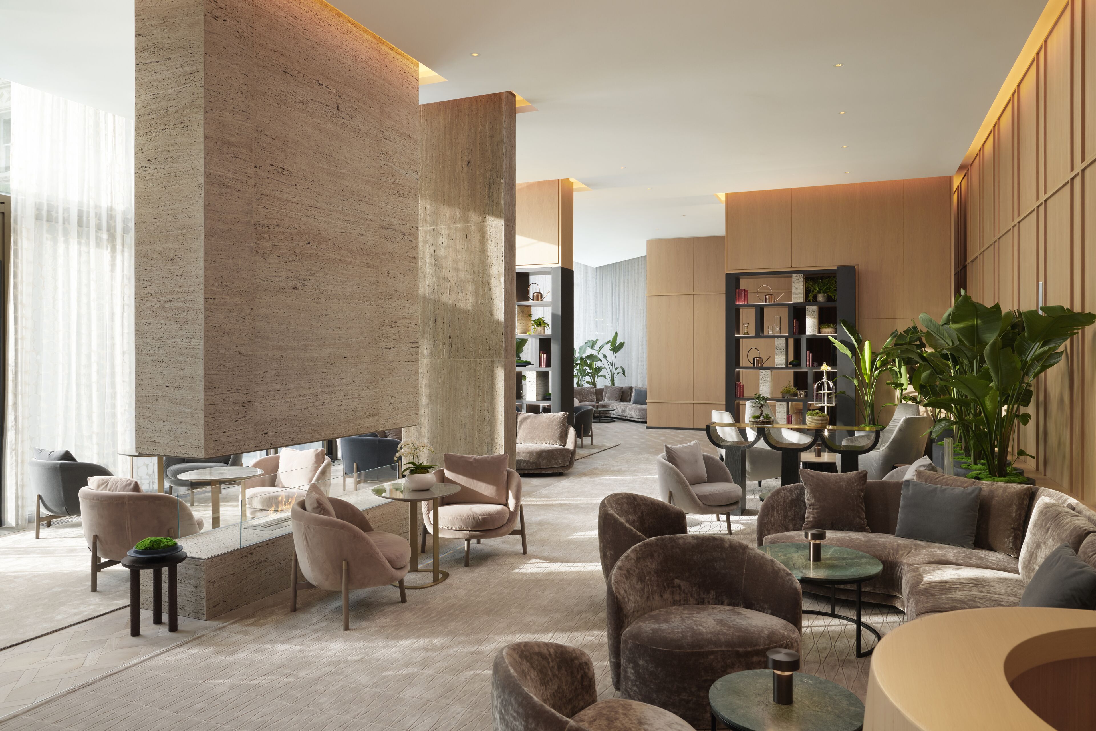 A modern lounge area with sofas, tables, and a bookshelf.