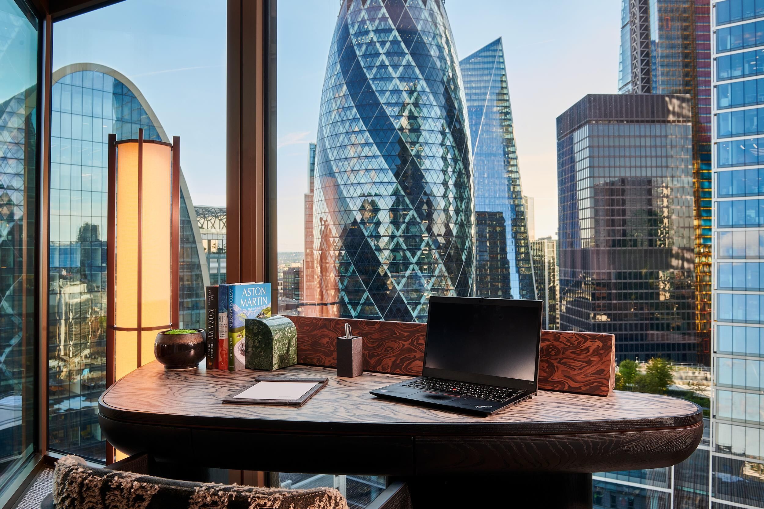 Ein moderner Arbeitsplatz mit einem Laptop, Büchern und Dekorationen auf einem runden Tisch mit Blick auf die Stadt.