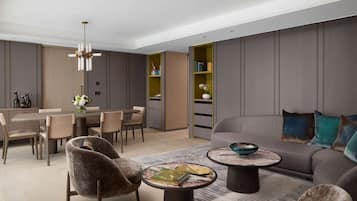 A modern living room with a sofa, armchairs, a dining table, and a bookshelf.