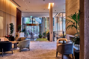 A modern lobby with a central seating area, a glass door entrance, and a view of the outdoor area. - Pan Pacific London (London)