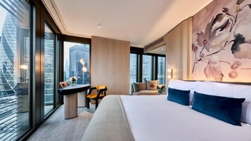 Ein modernes Hotelzimmer mit einem großen Bett, einem Schreibtisch und Blick auf die Stadt.