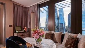 A modern living room with a marble coffee table, a sofa with patterned cushions, a blue chair, and a vase of flowers. - Pan Pacific London (London)