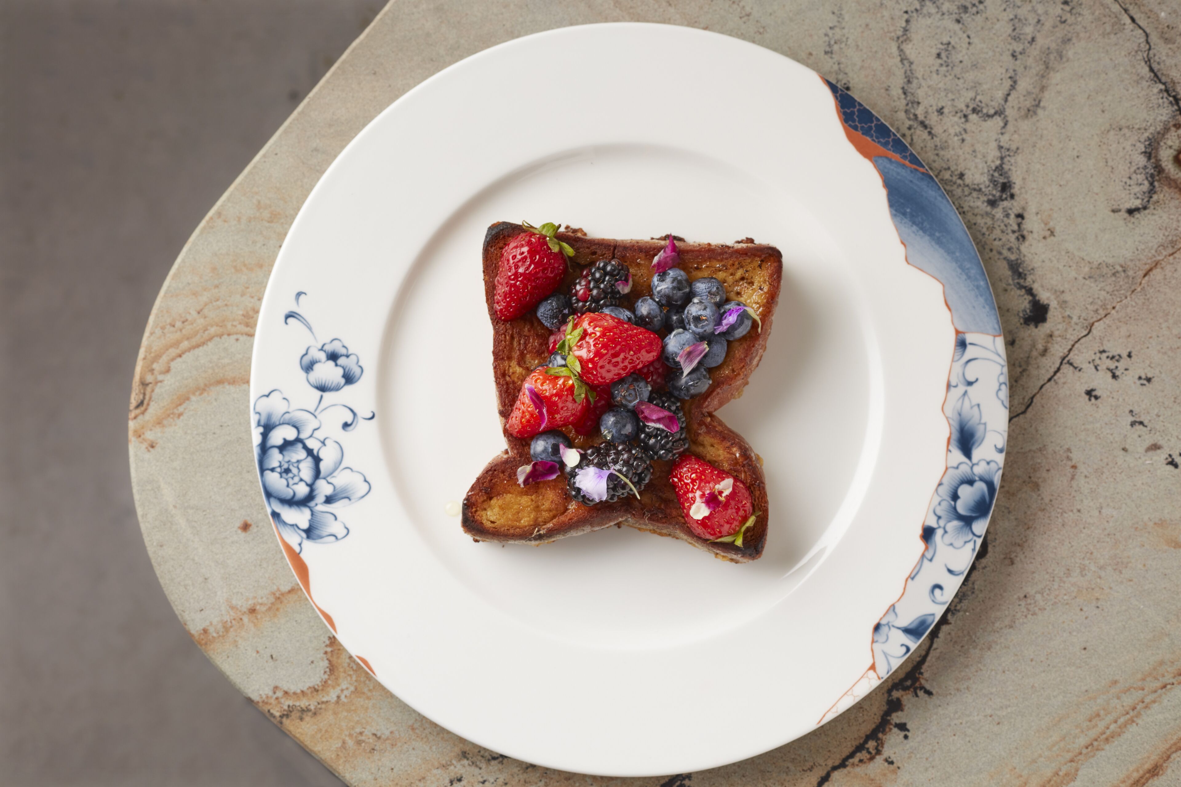 Ein Teller mit Toast, belegt mit Erdbeeren, Blaubeeren und Brombeeren.