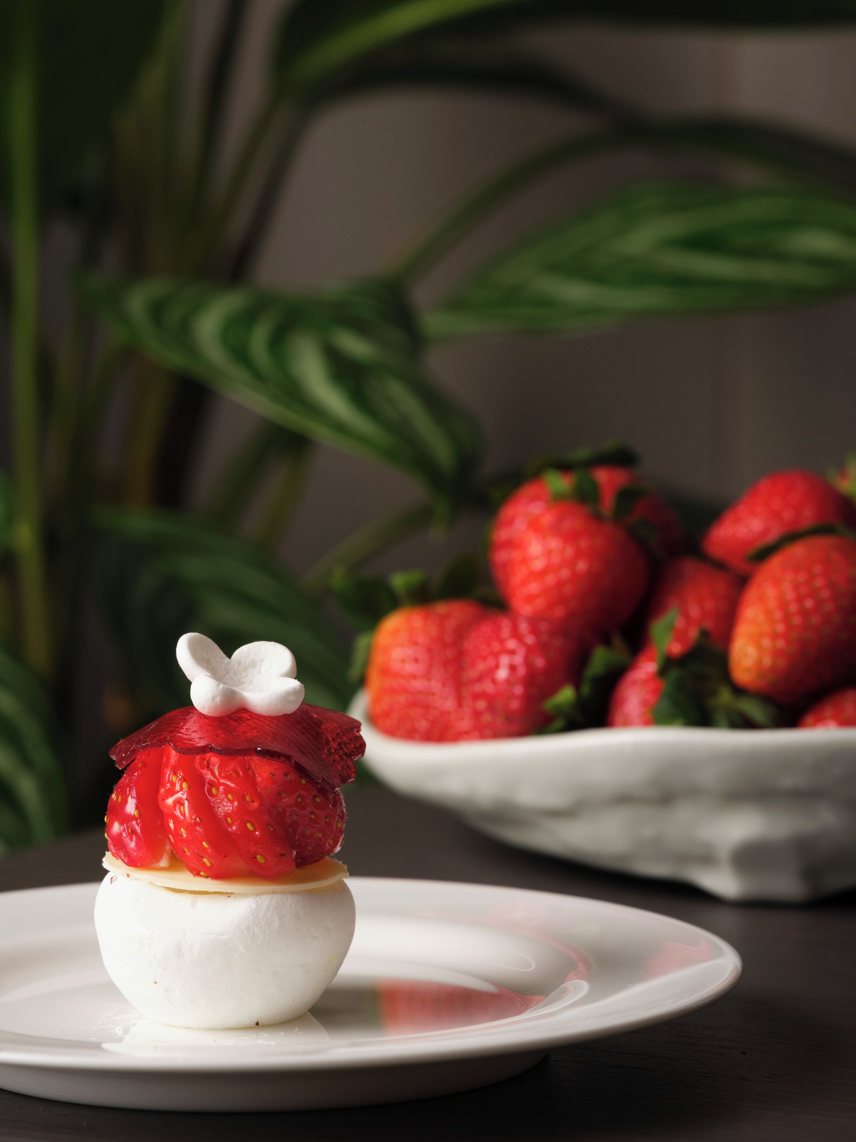 Dessert auf einem Teller, im Hintergrund Erdbeeren.