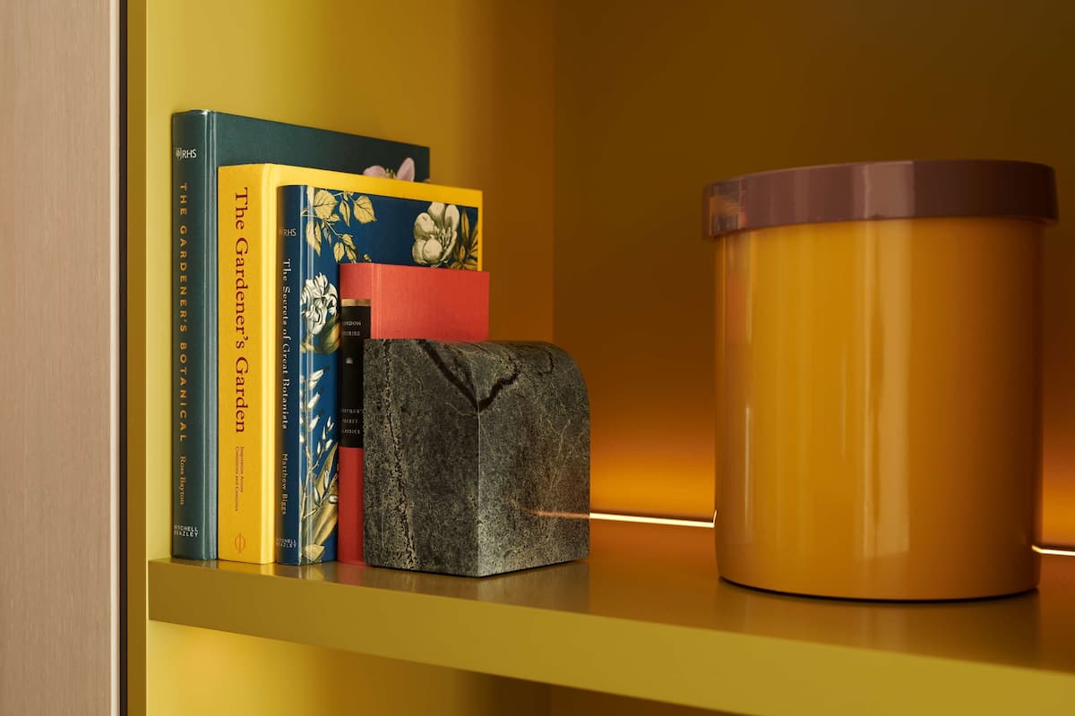 A shelf with books and a container.