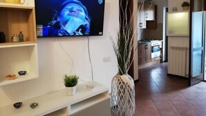 Eine moderne Küche mit einem an der Wand befestigten Flachbildfernseher, einem weißen Konsolentisch mit Dekoration und einer hohen Ziervase.
