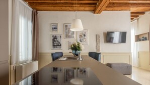 A modern dining area with a long table, chairs, a hanging light fixture, and artwork on the walls. - Lion Palace Superior R&R (Venecia)