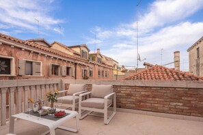 A terrace with a table set for dining, outdoor seating, and a brick wall. - Lion Palace Suite Terrace R&R (Venecia)