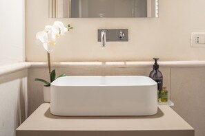 A bathroom with a white sink, a mirror above it, and a potted orchid beside the sink. - Lion Palace Suite Terrace R&R (Venecia)