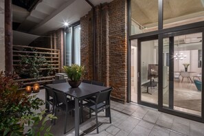 Uma área de refeições moderna com parede de tijolos, cerca de madeira e plantas em vasos.