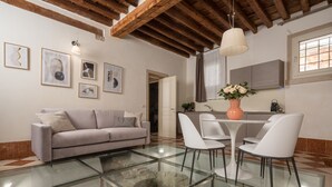 A modern living room with a glass coffee table, white chairs, a grey sofa, and artwork on the walls. - Lion Palace Deluxe R&R (Venecia)