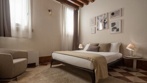 A bedroom with a bed, a chair, a lamp, and artwork on the wall. - Lion Palace Deluxe R&R (Venecia)